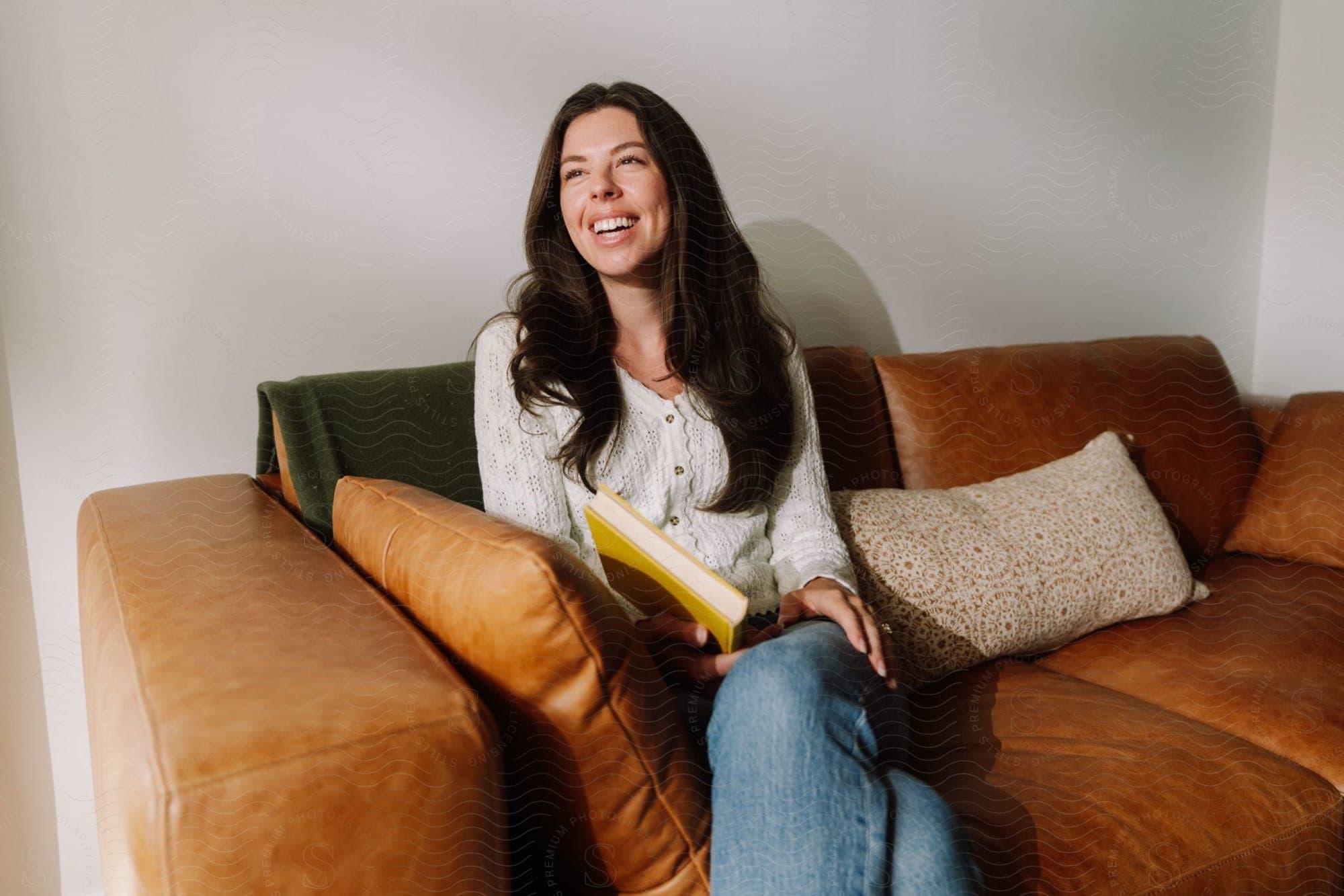 Celeste Curiel smiling on a sofa with a book in her lap